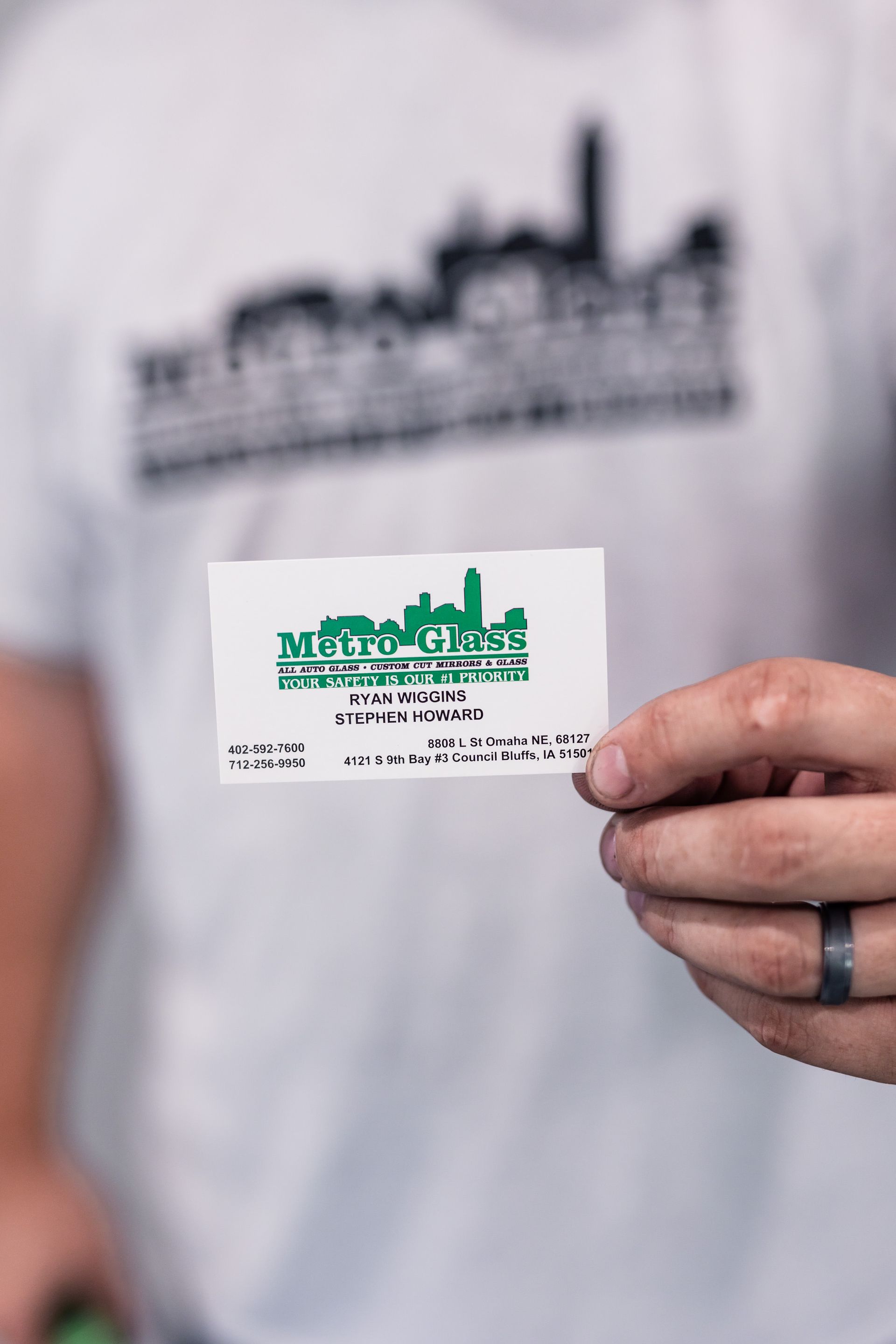 Person holding a business card with a green skyline logo. The card is white, and the person wears a white shirt.