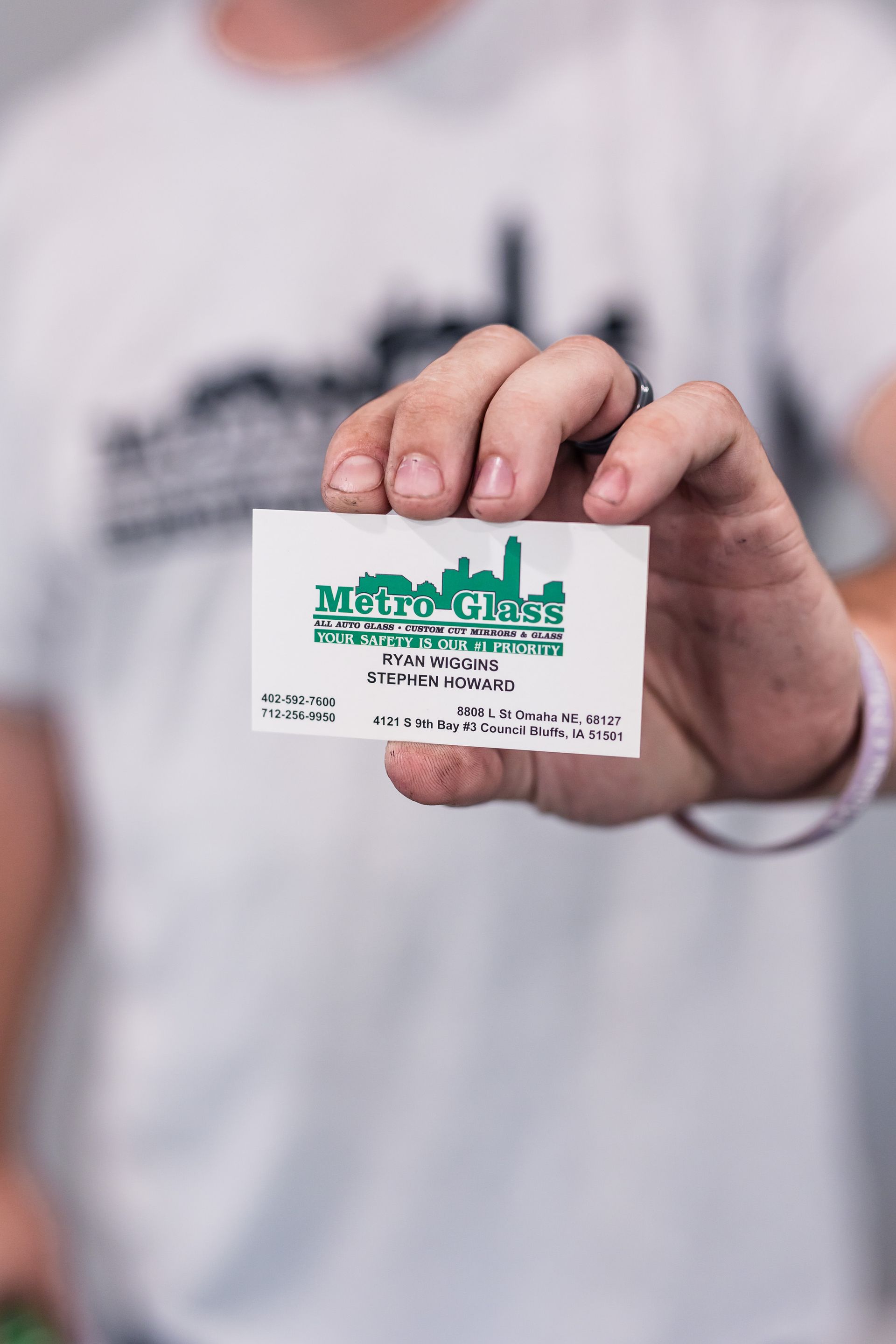 Person holding a small, white card with a green logo of a city skyline; possibly a ticket or promotional material.