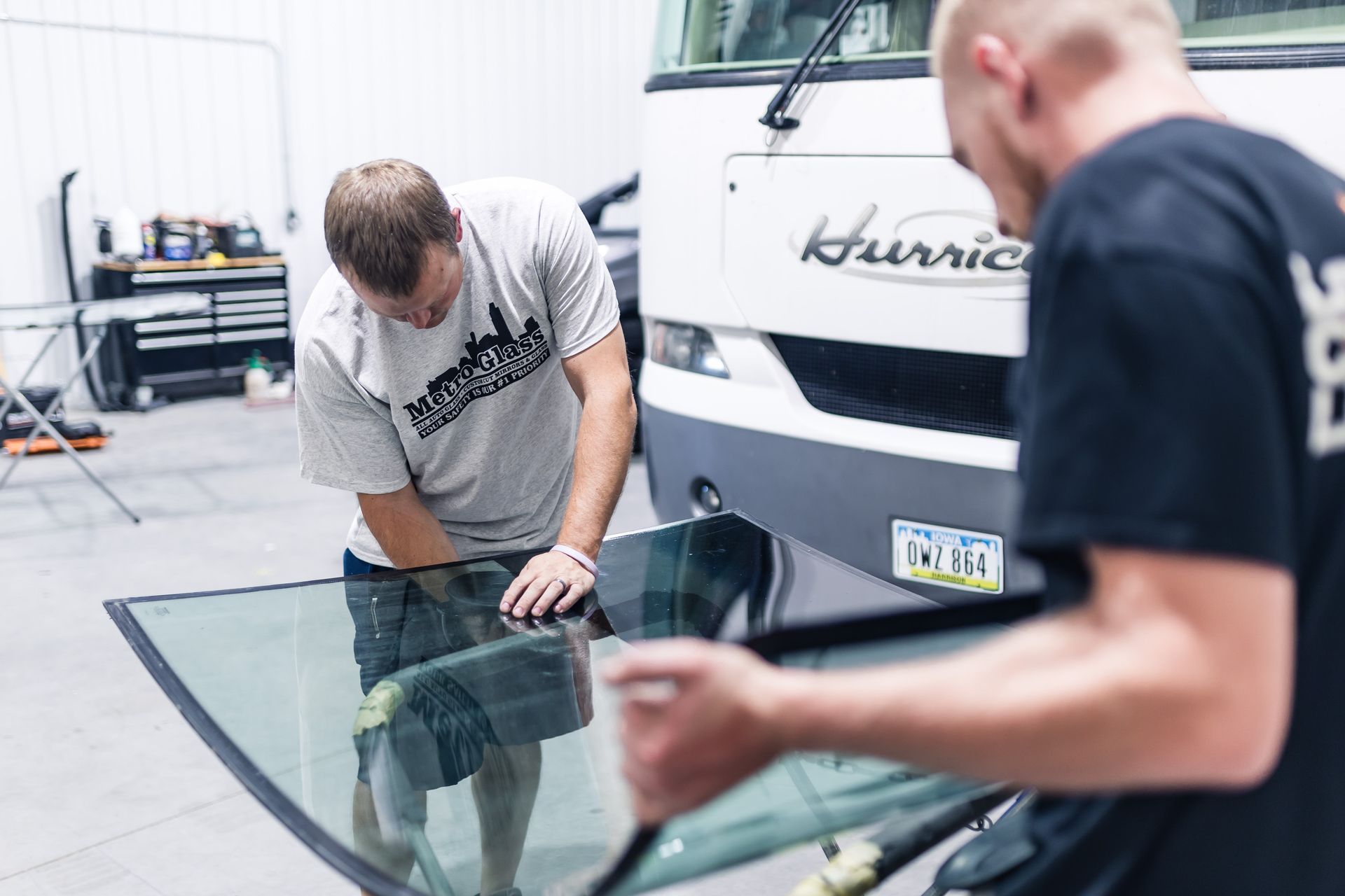 Two men installing a windshield on a 