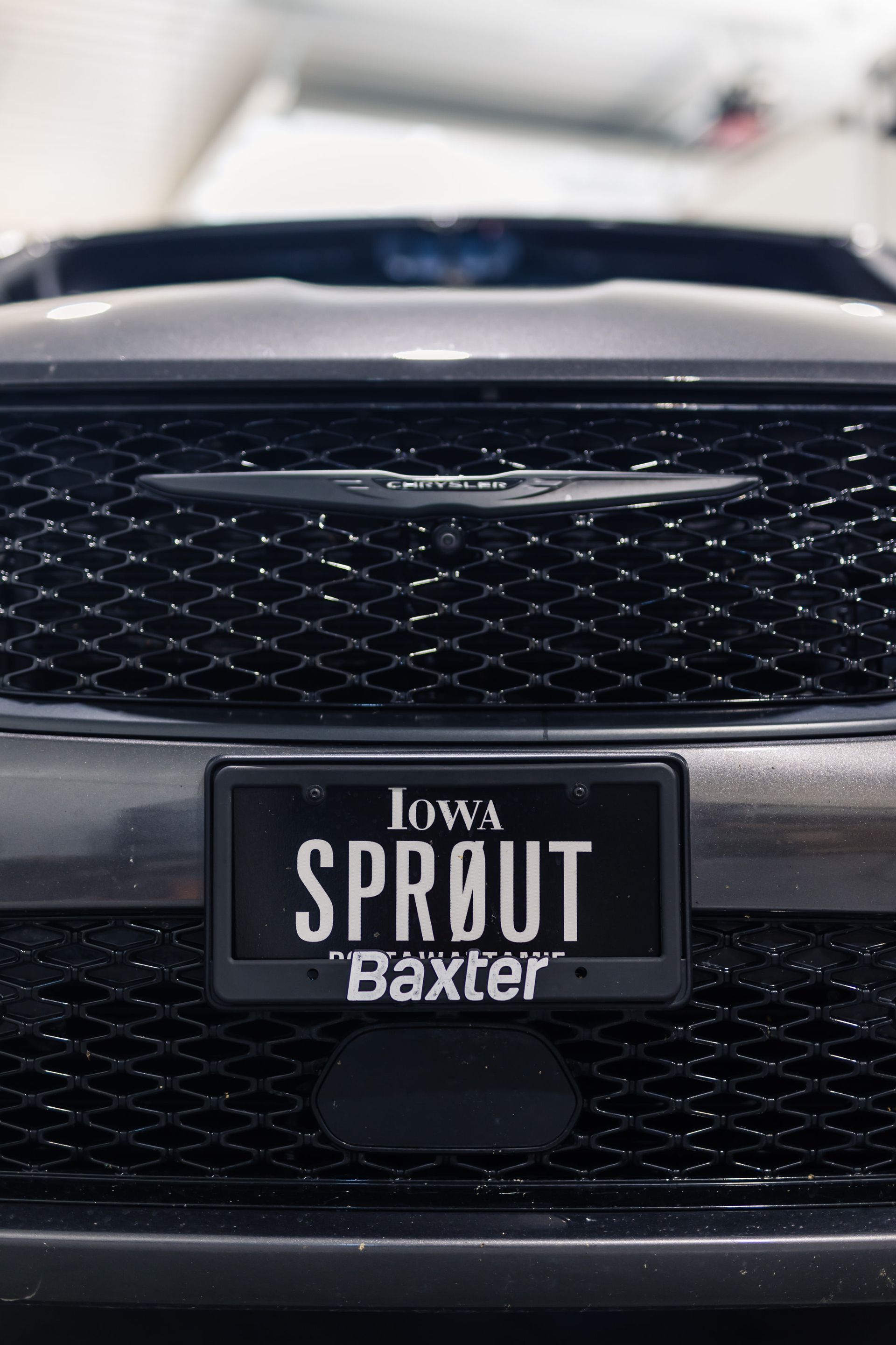 Close-up of a black Chrysler grille with an Iowa license plate reading 