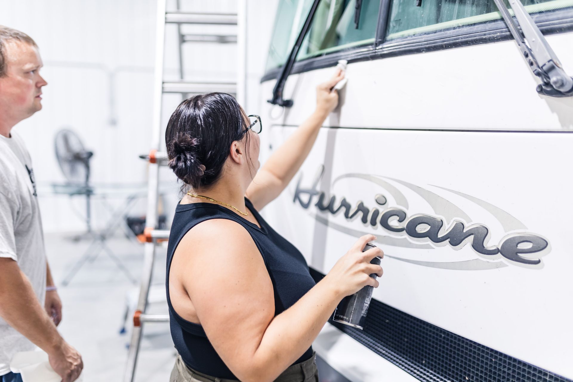 Two people cleaning a white RV with a 