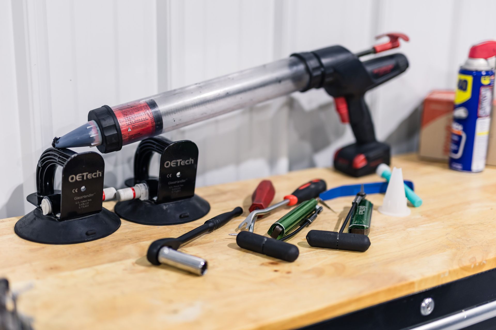 A workbench with various tools, including a caulking gun, suction cups, and screwdrivers.
