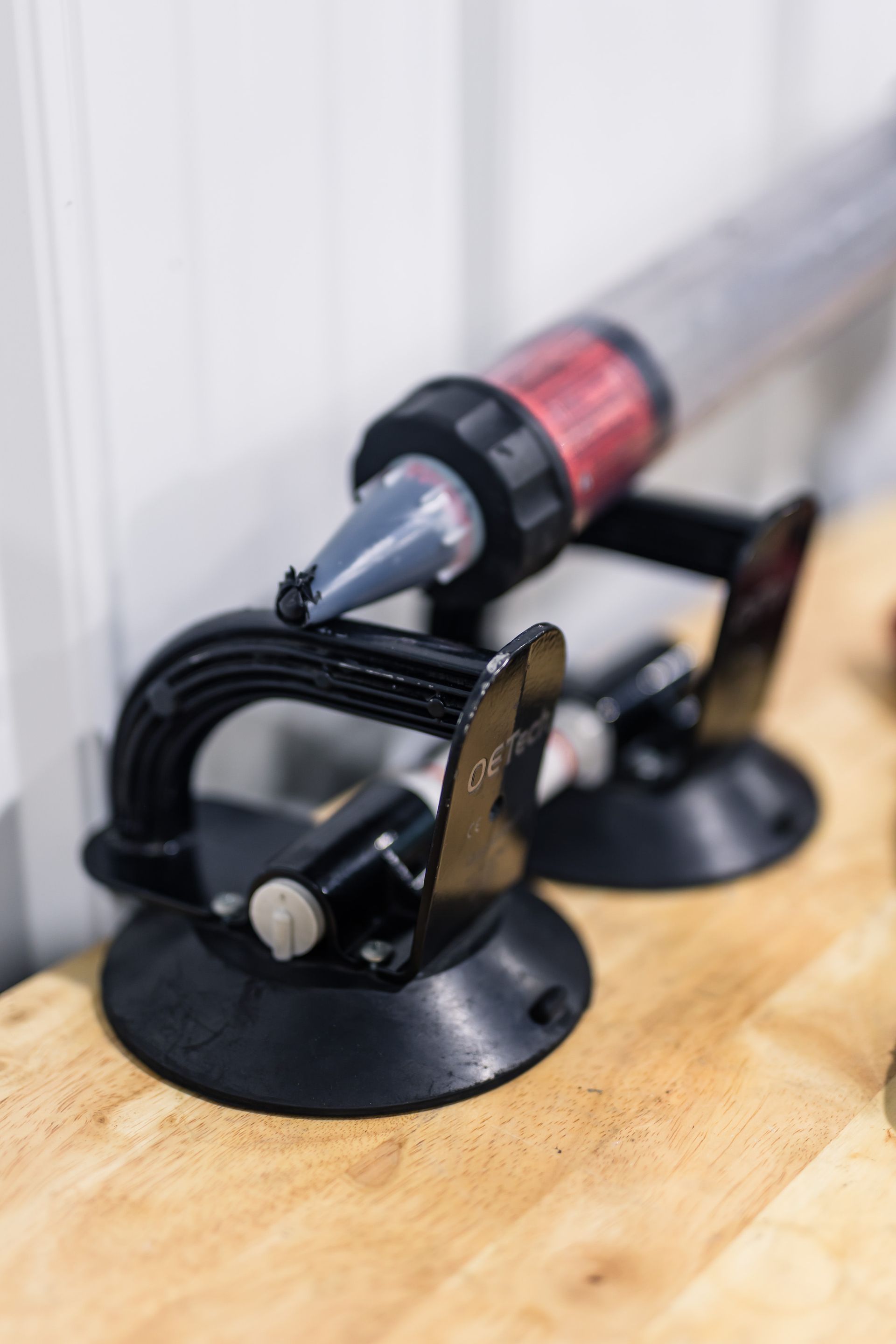 Two black suction cups hold a clear tube filled with red and gray material on a wooden surface.
