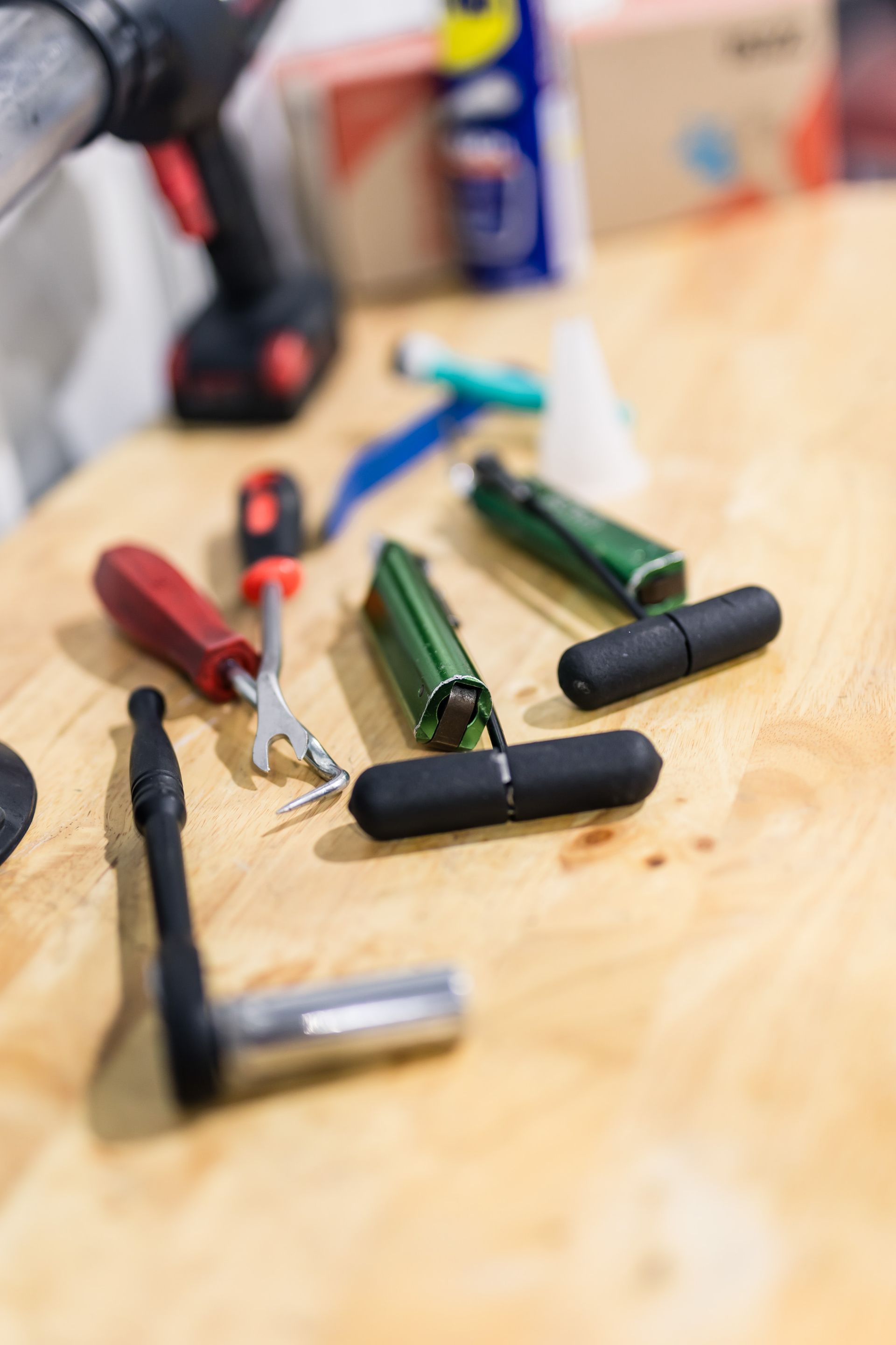 Tools arranged on a wooden surface including a ratchet, T-handles, screwdriver, and power drill.