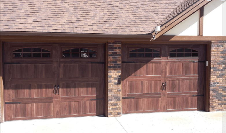 A house with two wooden garage doors and a brick wall