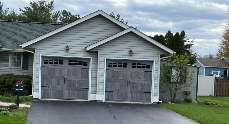 A house with two garage doors and a driveway in front of it.