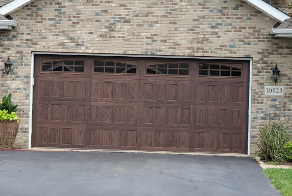 A large brown garage door is sitting in front of a brick house.