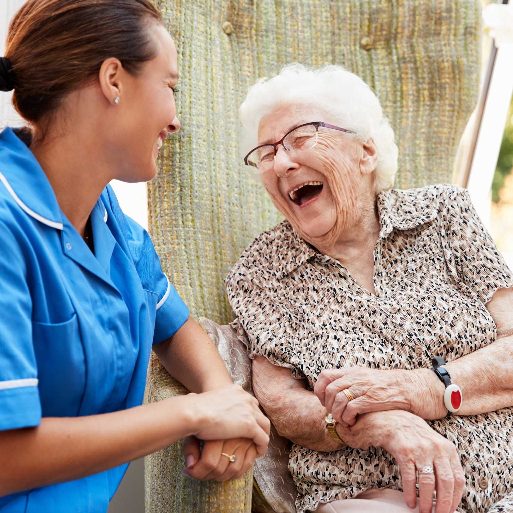 A nurse is talking to an elderly woman who is laughing