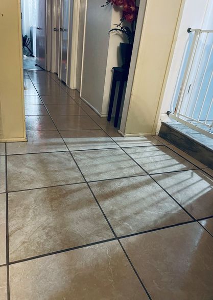 A hallway with a reflection of a window in the tile floor.