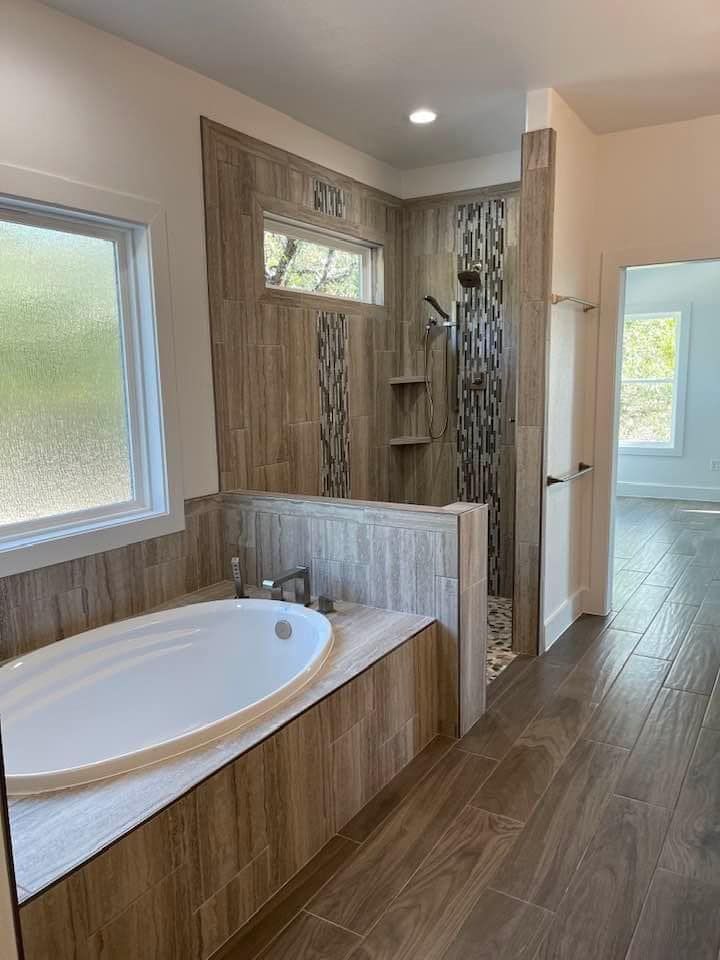 A bathroom with a tub , shower and window.