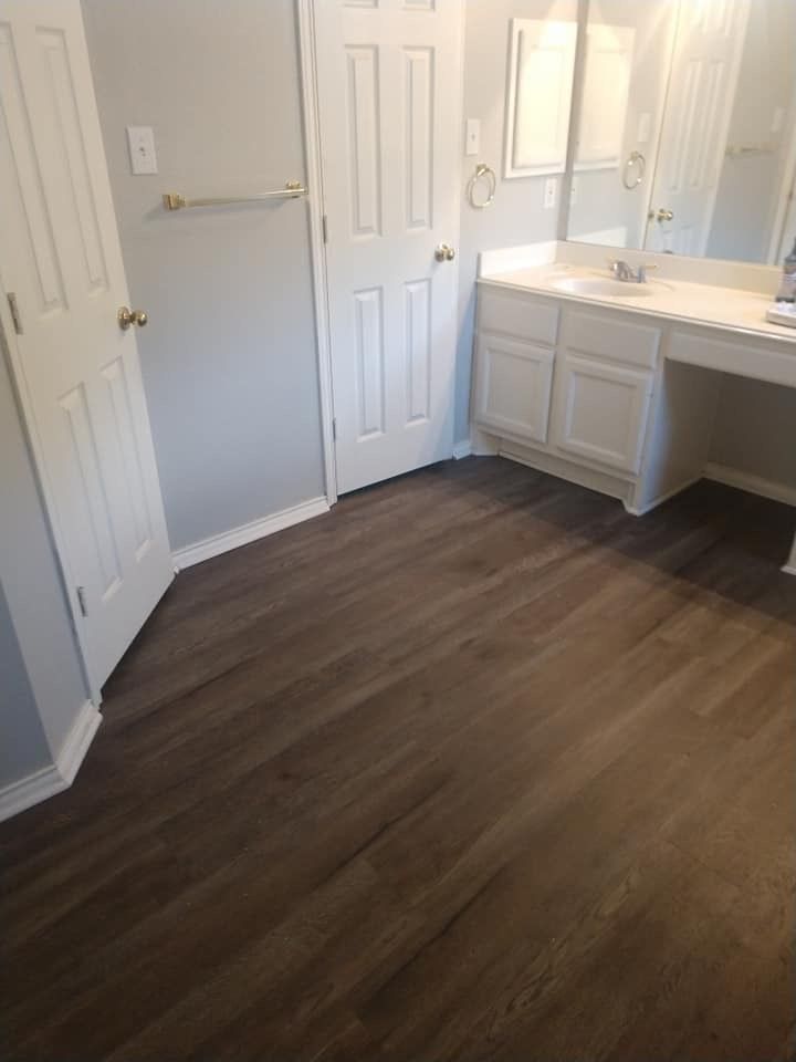 A bathroom with hardwood floors , a sink , and a mirror.