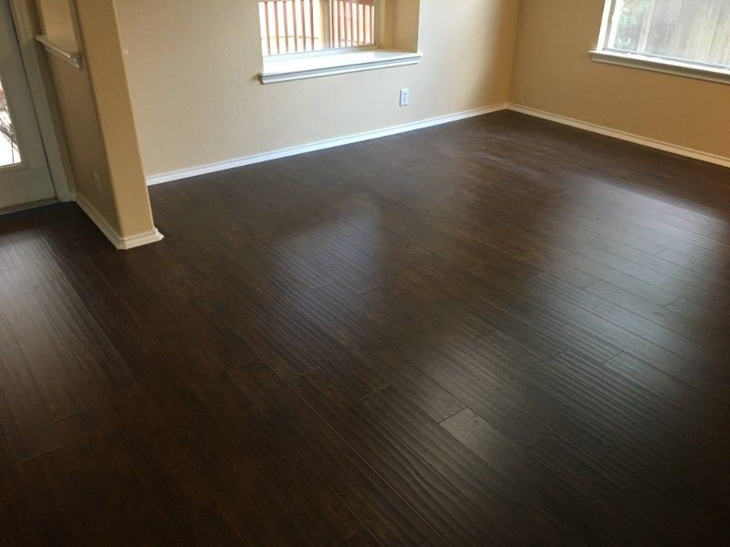 A living room with a wooden floor and two windows.