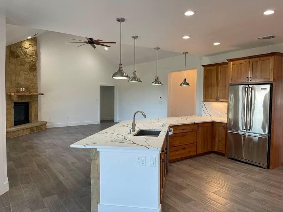 A kitchen with a stainless steel refrigerator , sink , and ceiling fan.