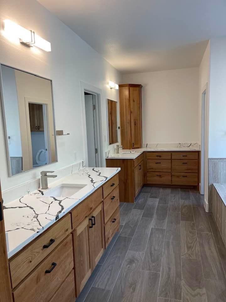 A bathroom with two sinks , a mirror , and wooden cabinets.