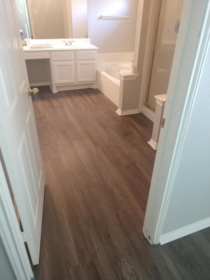 A bathroom with hardwood floors , a sink , a tub and a mirror.