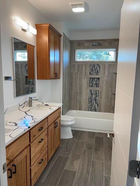 A bathroom with a sink , toilet , tub and mirror