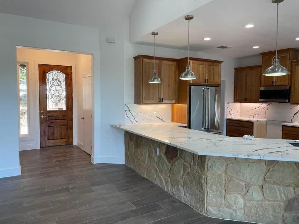 A kitchen with a stone counter top and wooden cabinets