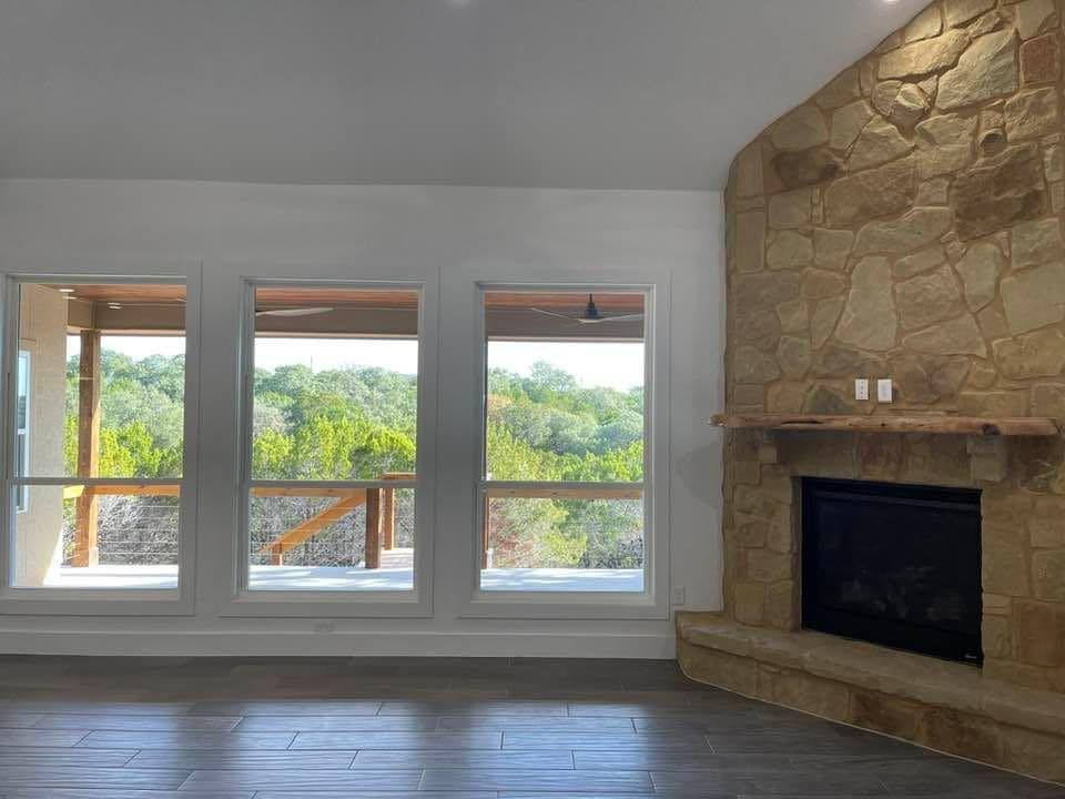 An empty living room with a fireplace and lots of windows