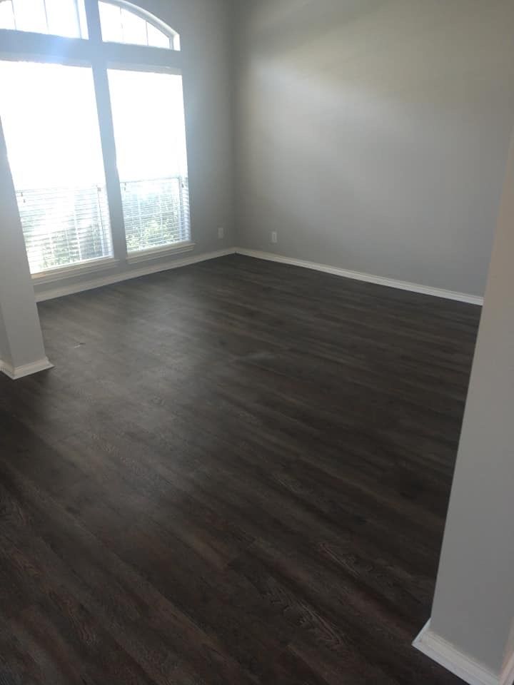 An empty living room with hardwood floors and a large window