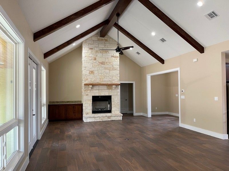 An empty living room with a fireplace and ceiling fan