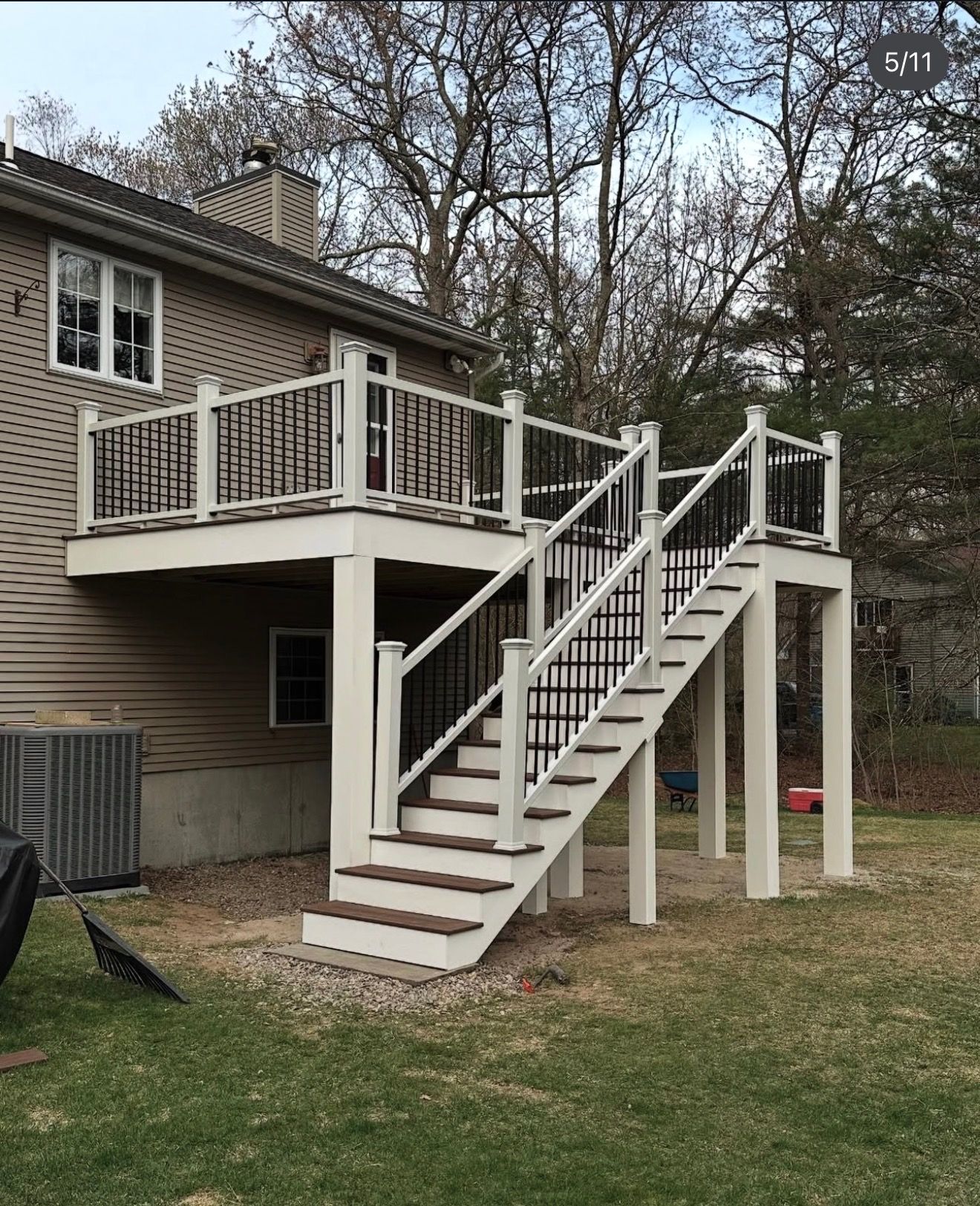 Backyard deck with white stairs and railing attached to a brick house