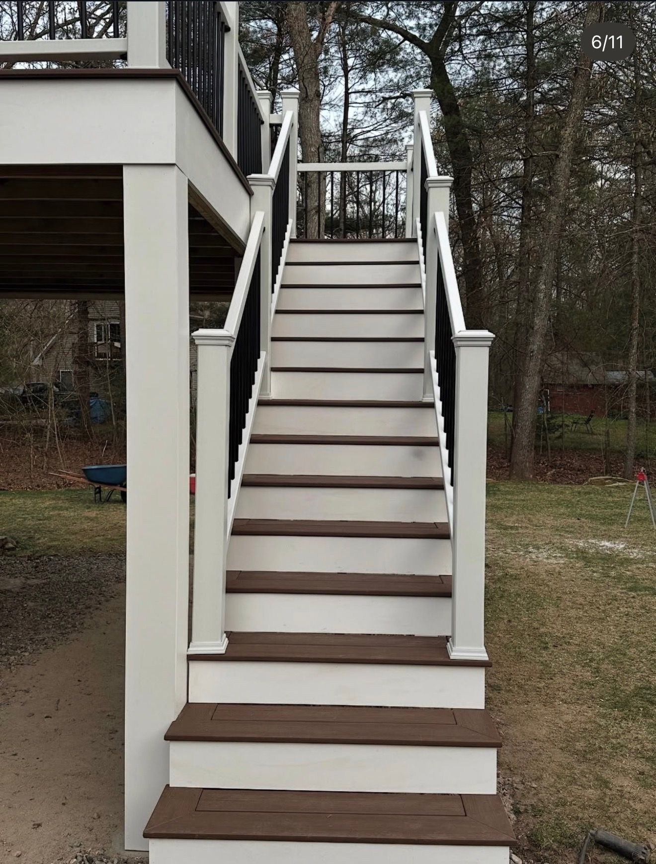 Front view of outdoor wooden staircase with white railings leading up to a deck