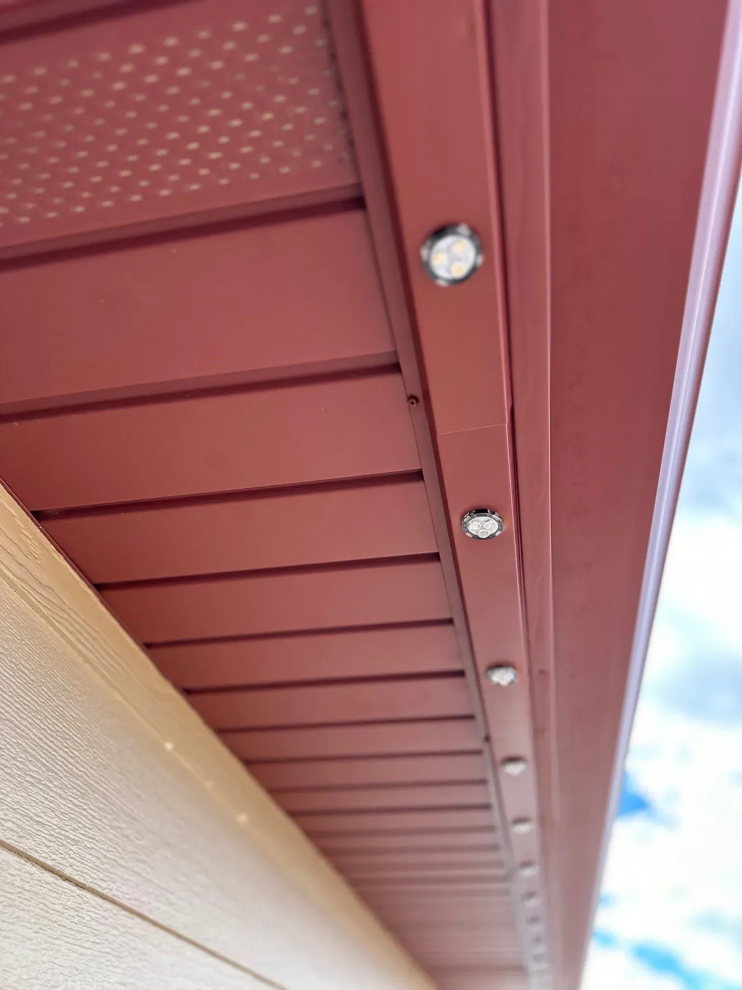 Red soffit with recessed lights, adjacent to light-colored siding.