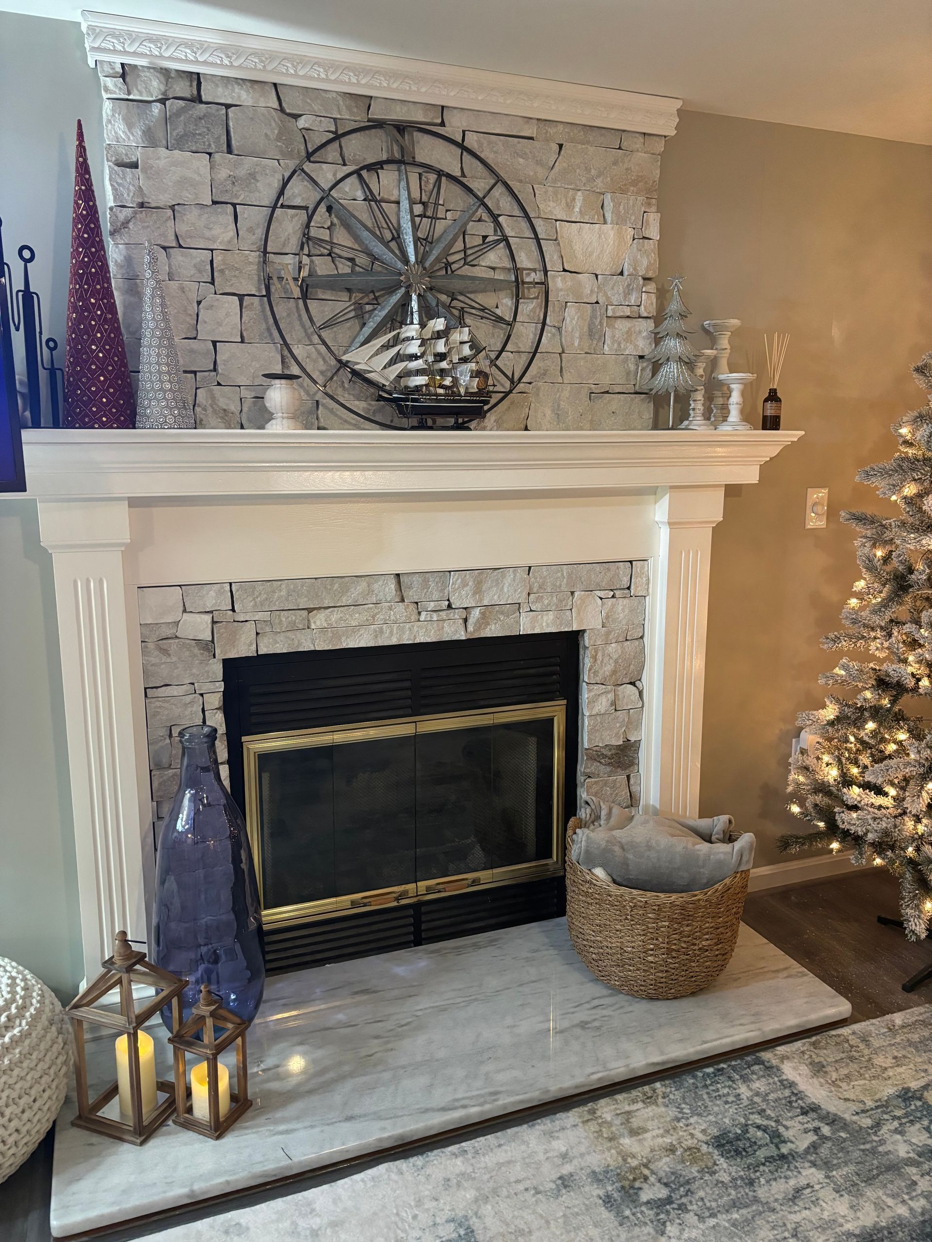 Fireplace with stone facade, decorative nautical elements, and Christmas tree.