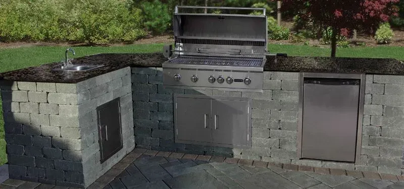 Outdoor kitchen with grill, sink, and appliances built into stone.