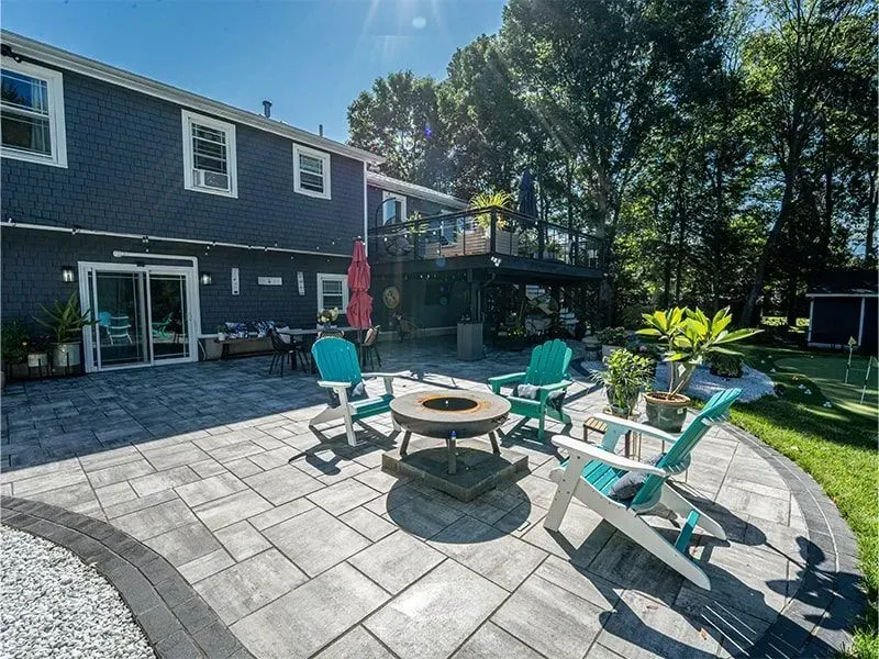 Backyard patio with turquoise chairs, fire pit, and a dark blue house.