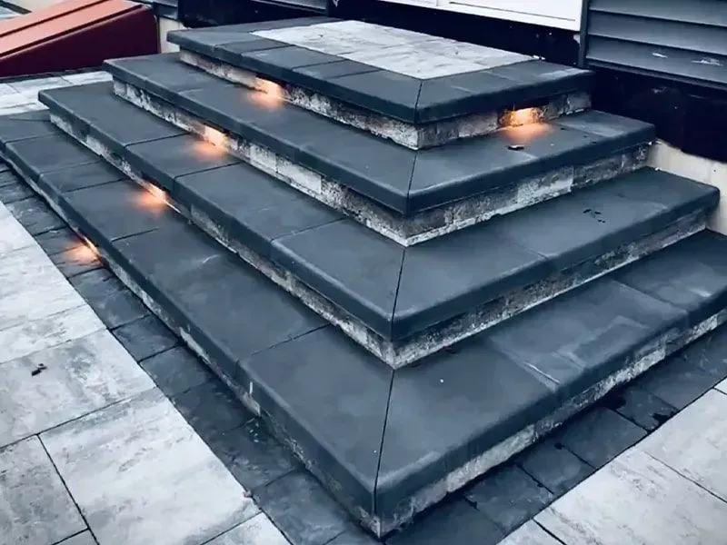 Stone steps with built-in lights, leading up to a platform. Dark grey stone with lighter edging.