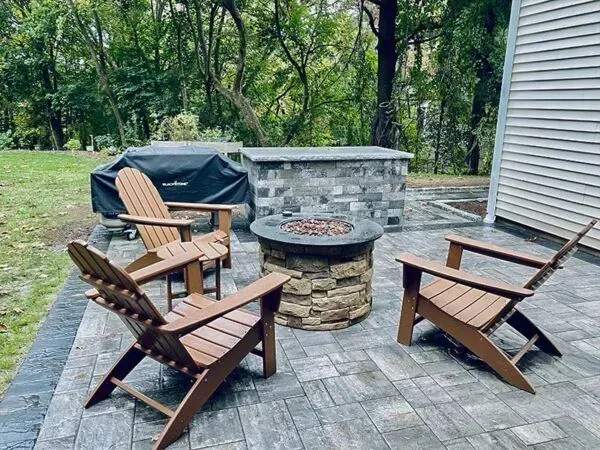 Patio with brown Adirondack chairs, a fire pit, and stone grill station.