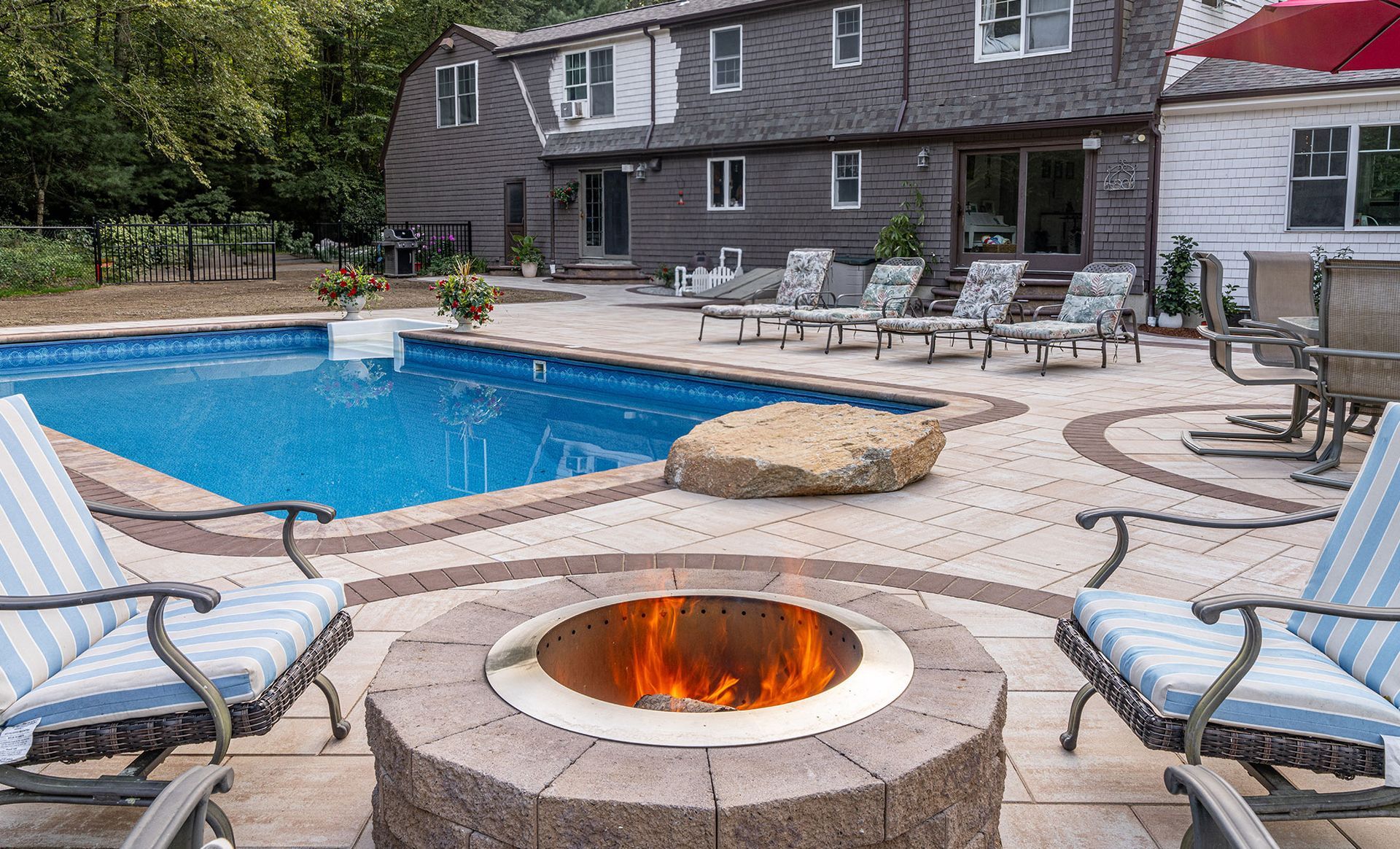 Backyard with pool, fire pit, lounge chairs, and two-story house.