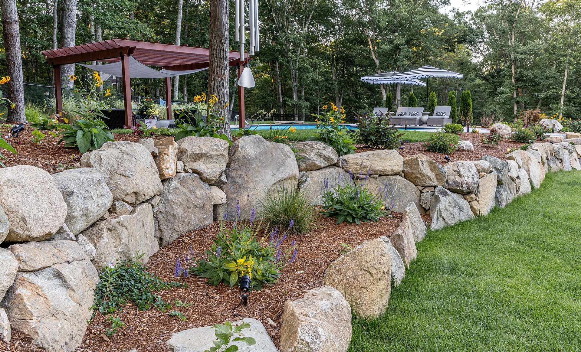 Stone retaining wall with garden bed and pool area.