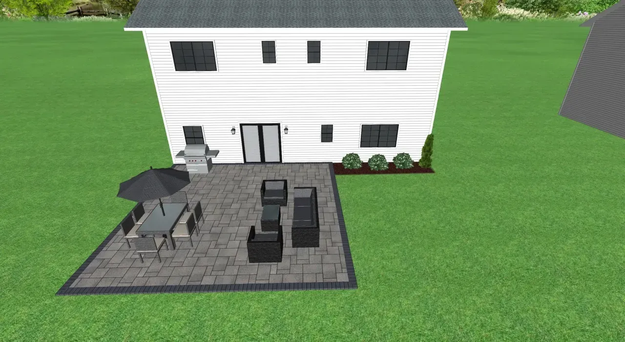 Backyard patio with gray pavers, black furniture, and white house with black shutters on green grass.