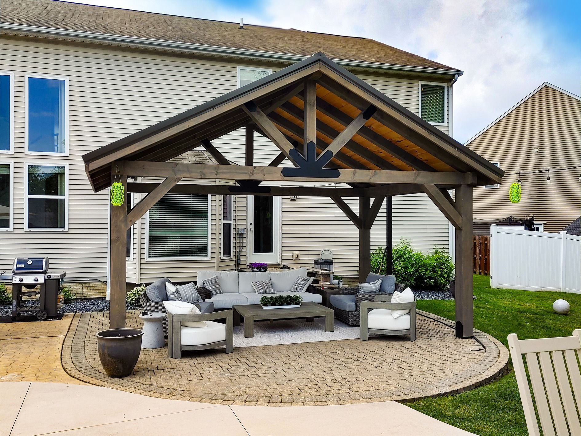 Outdoor patio with a wooden pergola, seating area, and a beige stone base.