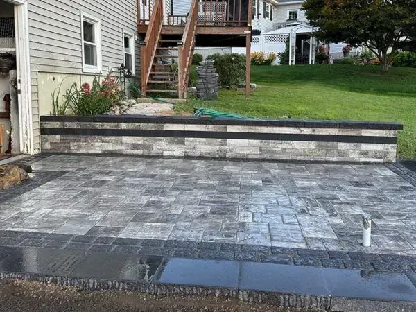 Brick patio with retaining wall, stairs, and grass in the background.