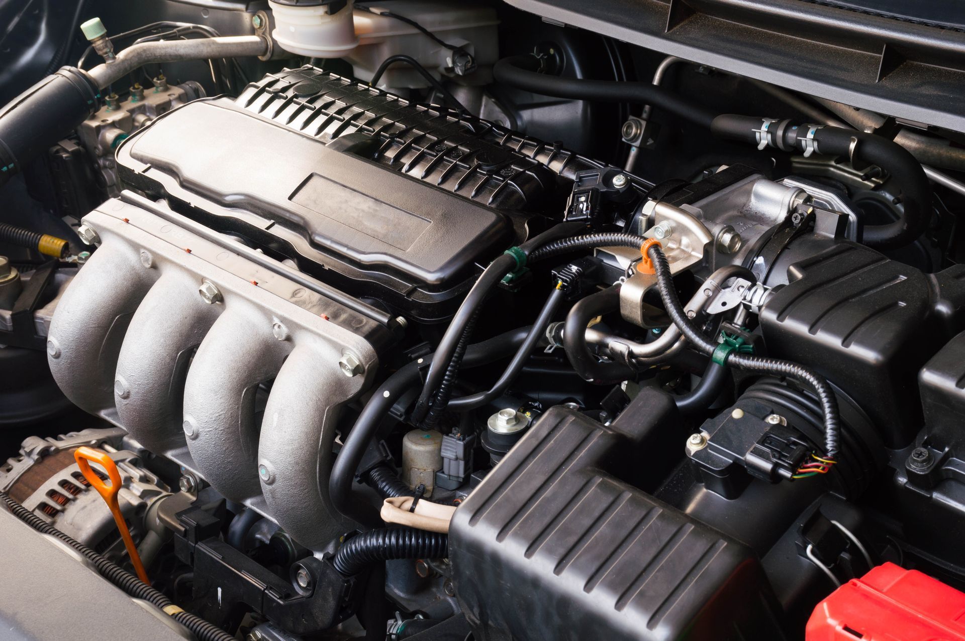Car engine bay with black intake manifold, hoses, and air filter box under the hood