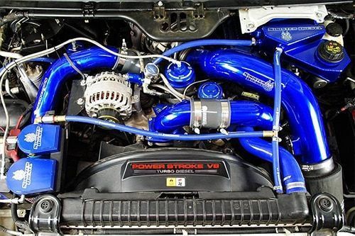 Modified car engine bay with blue intake pipes and black cover
