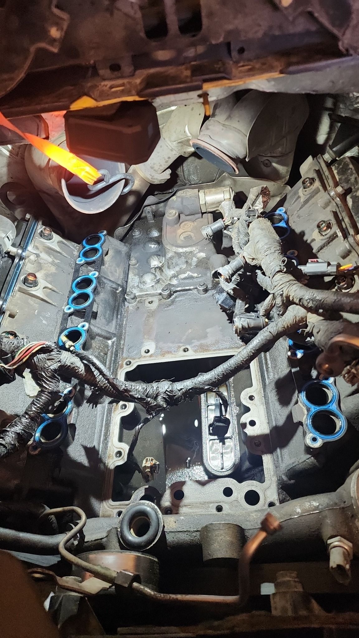 Glowing orange flame inside a car engine bay with exposed metal parts and blue fasteners