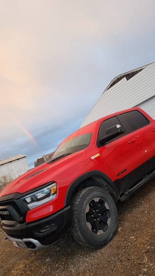 Red pickup truck parked beside a building under a cloudy sky