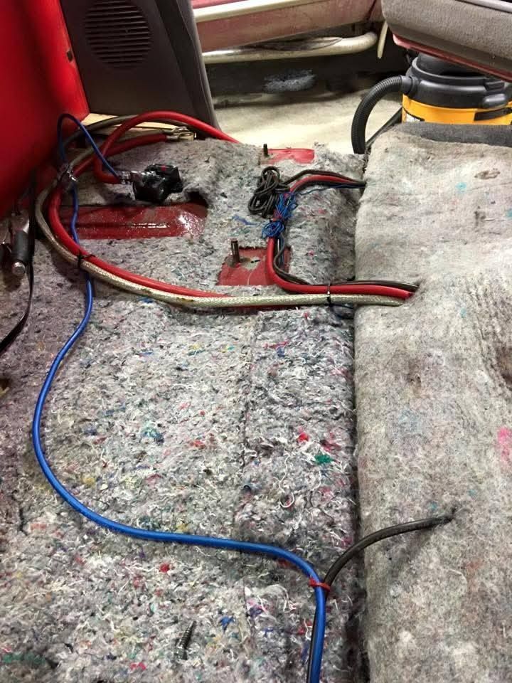 Exposed melted wires and damaged wiring on a carpeted floor under a chair
