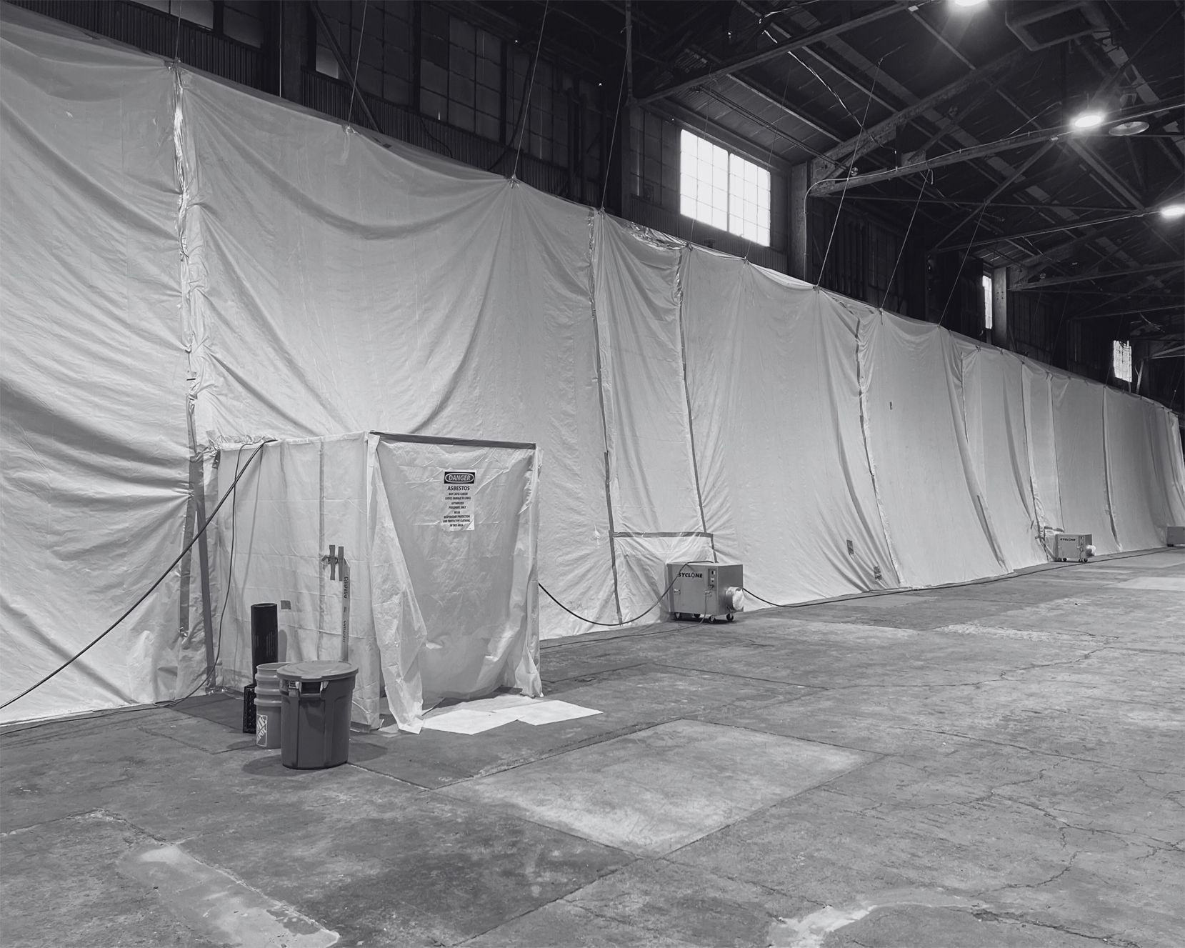 Large warehouse with long white curtain walls and a doorway. Black and white.
