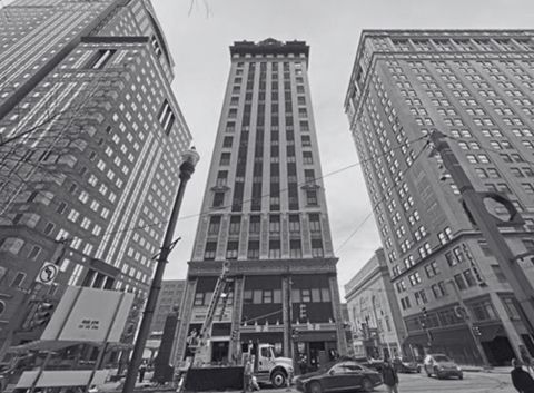 Black and white photo of tall buildings in a city, including the Frick Building in Pittsburgh.