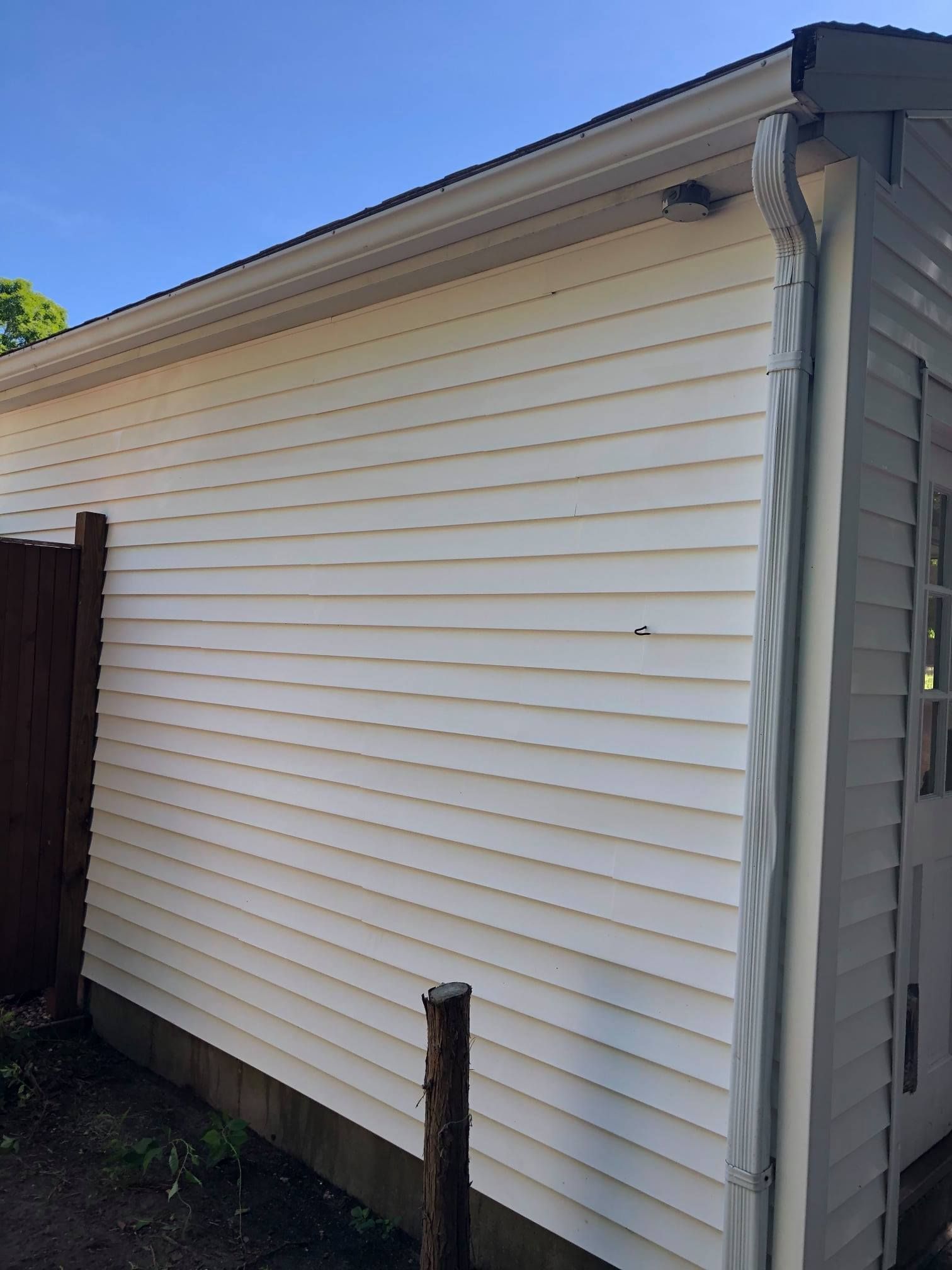 White siding on a building with gutter and dark trim.