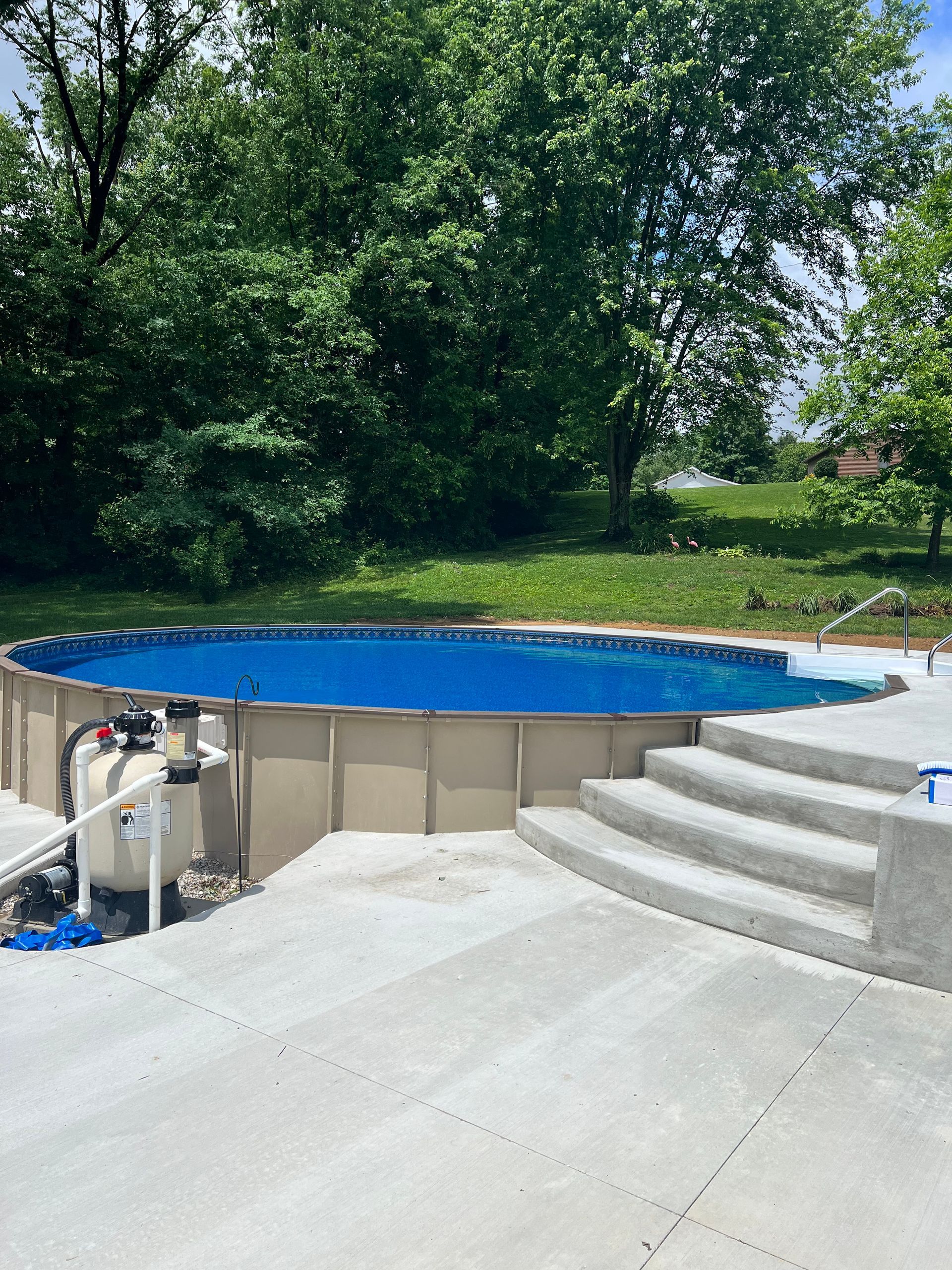A large swimming pool is sitting on top of a concrete patio.