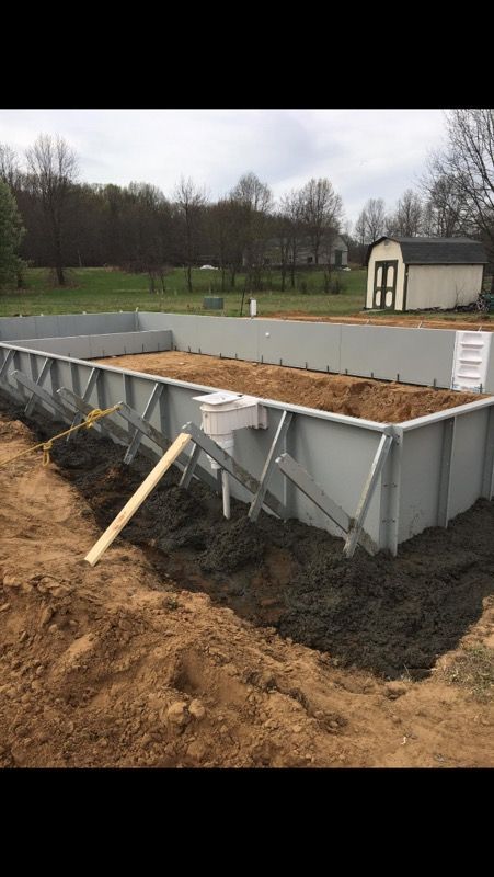 A large swimming pool is being built in a dirt field.