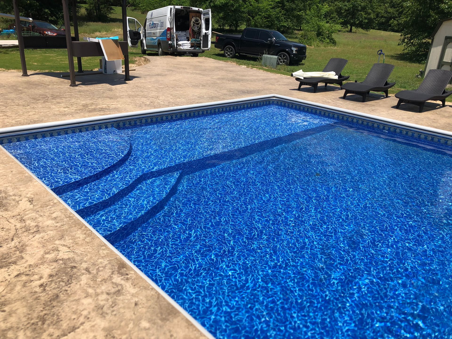 A large swimming pool surrounded by chairs and a truck.