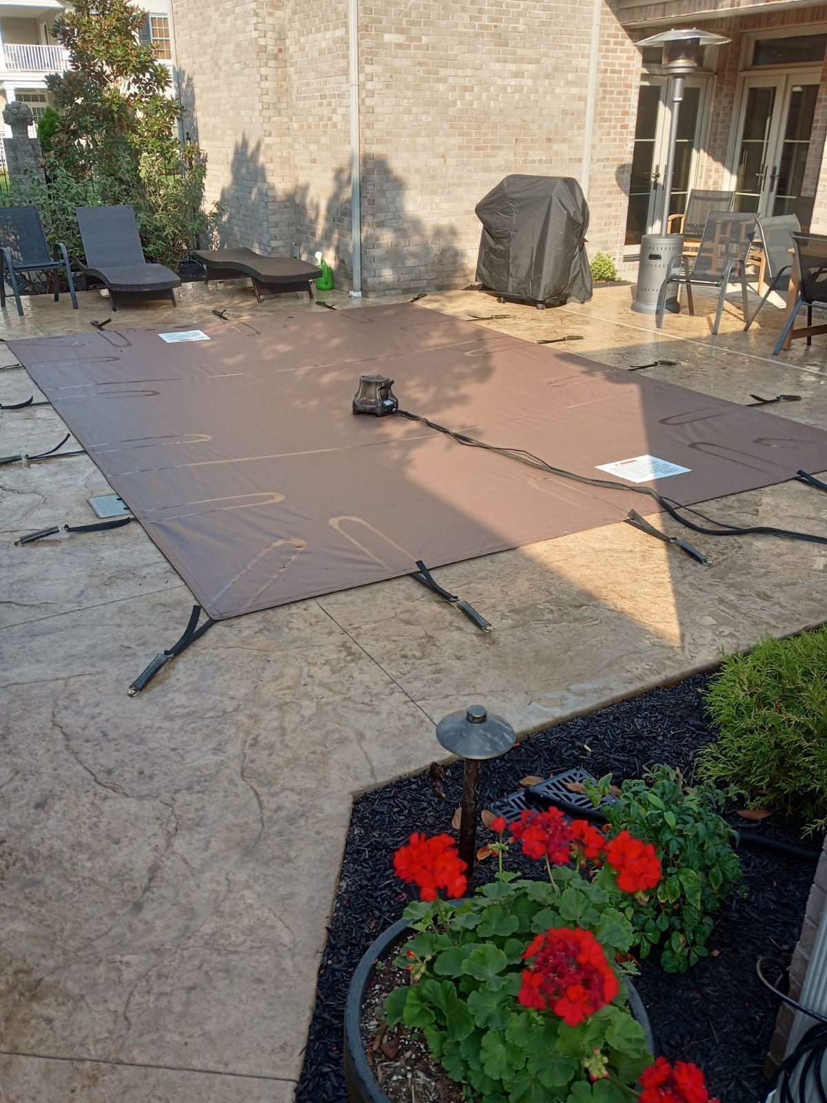 A large brown tarp is sitting on top of a concrete patio.