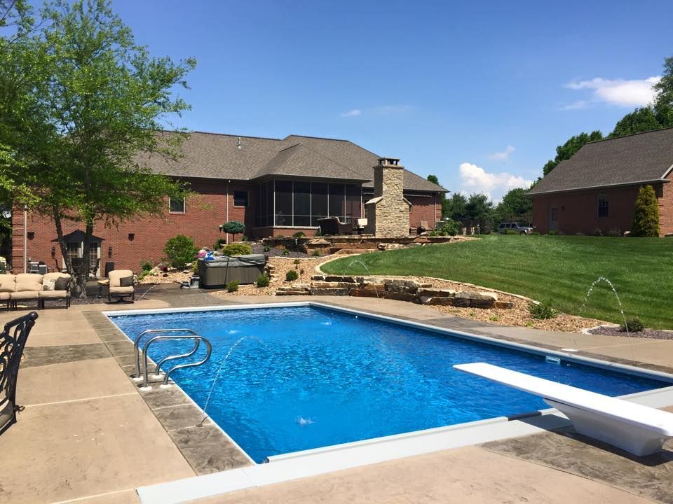 There is a large swimming pool in the backyard of a house.